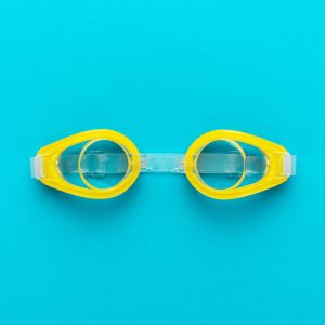 Yellow Swimming Goggles Over Blue Background With Central Composition