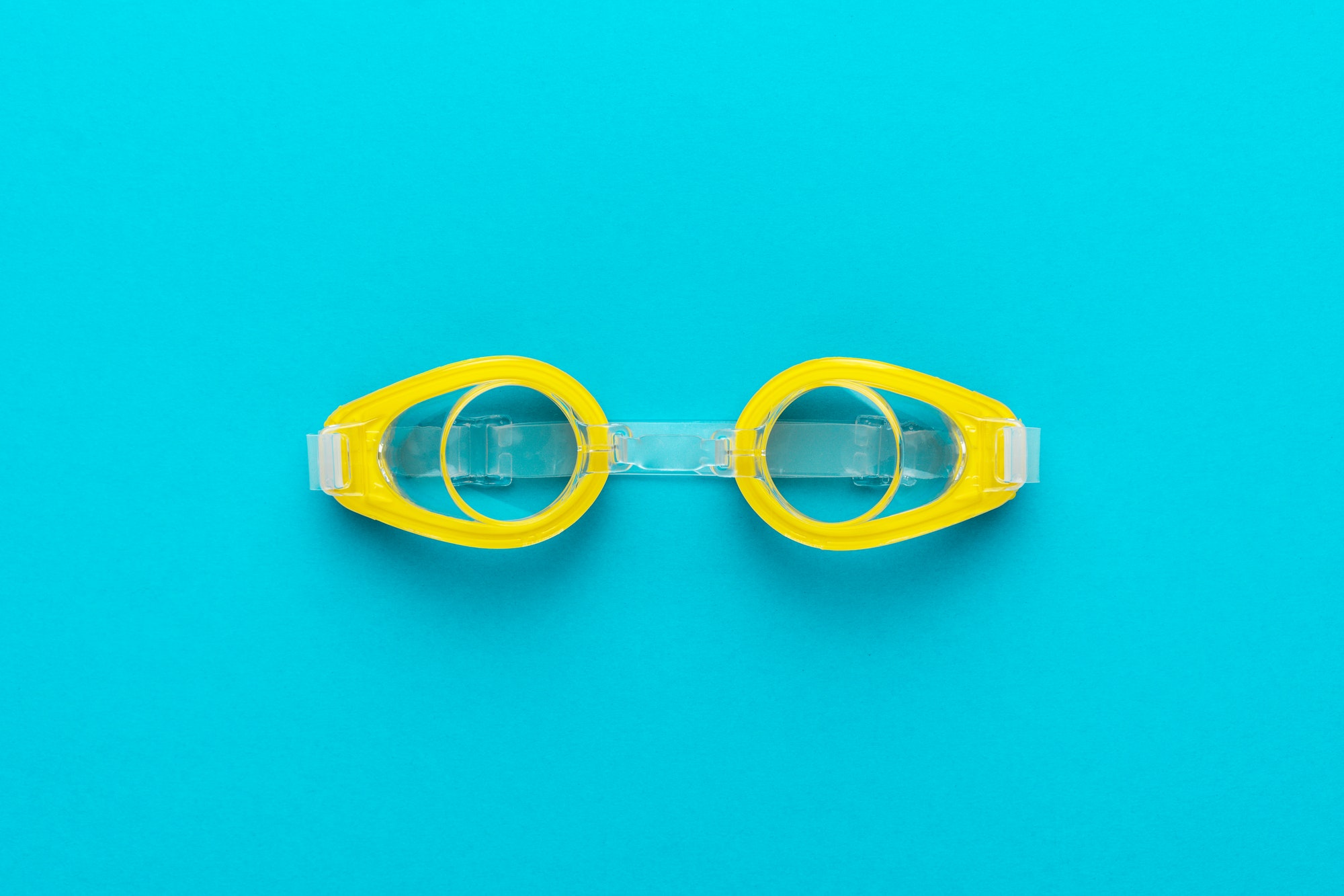 Yellow Swimming Goggles Over Blue Background With Central Composition